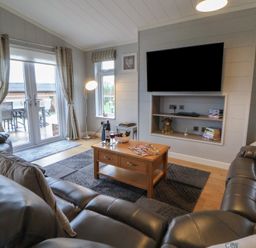 A living room with a sofa and coffee table at Holly Lodge in Lloc near Caerwys