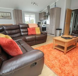 A living room with a sofa and coffee table at Pine Lodge in Lloc near Caerwys