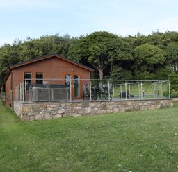 A cabin with a deck and garden at Pine Lodge in Lloc near Caerwys
