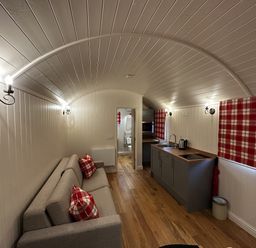 A living room with a sofa and kitchenette at The Lodge in Upton Warren