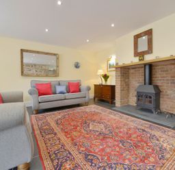 A living room with a sofa and fireplace at The Cider Barn at Home Farm Down Thomas near Wembury