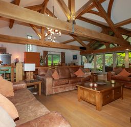 A living room with sofas, a coffee table, and a kitchen area at Kerslake House in Crafthole