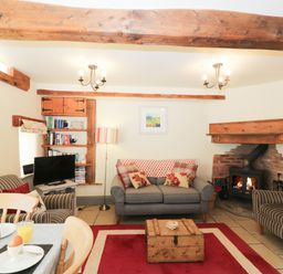 A living room with sofas a wooden chest coffee table a fireplace and a television at Honey Bee Cottage in Staintondale