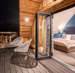 A bedroom with a bed and chairs on a balcony at The Lookout in Addingham