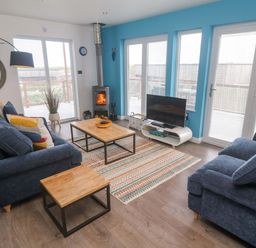 A living room with a sofa, coffee table and television at Pentewan - 67, Portreath