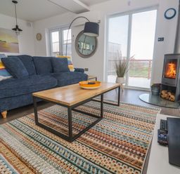 A living room with a sofa, coffee table, and fireplace at Pentewan - 67, Portreath