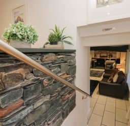 A stairwell with a stone wall and plants leading to a living area at Newlands Fell House, Newlands near Keswick