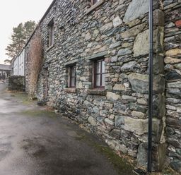 A stone building with windows and a pathway at Newlands Cottage in Keswick