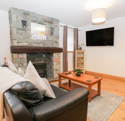 A living room with a fireplace and sofa at Newlands Cottage in Keswick