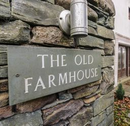A sign on a stone wall at The Old Farmhouse in Cockermouth