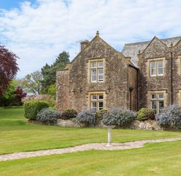 An outdoor view of a stone building with garden at Dowrich West Wing Apartment in Crediton
