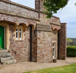 An exterior view of a stone building with a green door at Dowrich West Wing Apartment in Crediton