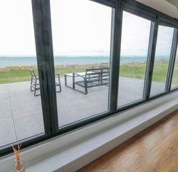 A living room with a view of the patio and sea at Pengarnedd Amlwch