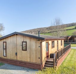 A log cabin with a deck and garden at Hazel Lodge in Craven Arms