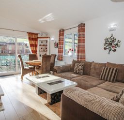 A living room with a sofa and dining area at Hazel Lodge Clunton near Clun