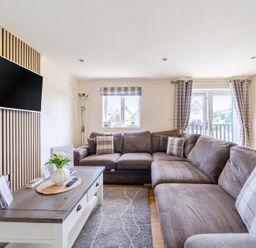 A living room with a sectional sofa and television at James Ville Marina Lodge 8 in Brigg
