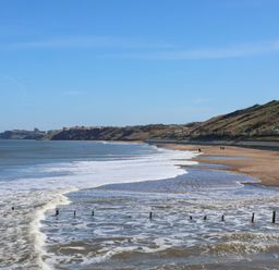 A beach with waves and cliffs at South Villa Sandsend near Whitby
