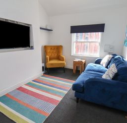 A living room with a blue sofa and yellow armchair at Apartment 3 in Scarborough