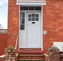 An entrance with a white door and brick wall at 16 Elmbank Gardens in Paignton