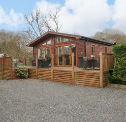 A wooden lodge with decking and outdoor seating at Waters Edge Lodge in Windermere