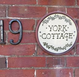 A house number and sign on a brick wall at York Cottage in Southwold