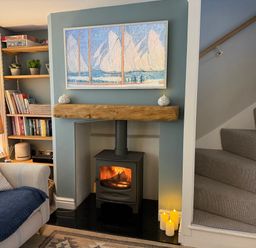 A living room with a fireplace and shelves filled with books at York Cottage in Southwold