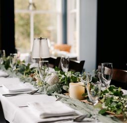 A dining table set with glasses and greenery at Picton House near St Clears