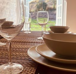 A dining table set with plates and glasses at Coach House near St Clears