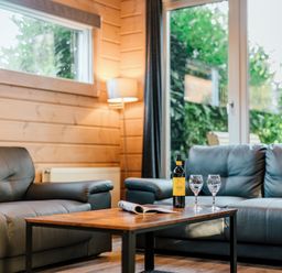 A living room with a table, sofa, and wine at Poplar Lodge (Pet) Thirsk
