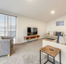A living room with a sofa, armchair, coffee table, and television at Sonnet 2 Spa Roof Terrace (Pet) in Carmarthen