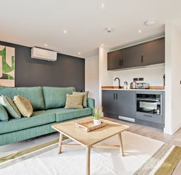 A living room with a sofa and kitchenette at Arvor Studio 1.0 Bude