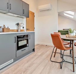 A kitchen with cabinets, microwave, toaster, and dining table at Whalesborough Penthouse 2.0 in Marhamchurch