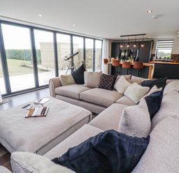A living room with a sofa and telescope at The Joiners Cottage in Birling near Warkworth