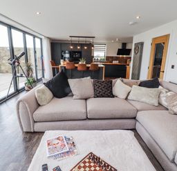 A living room with a sofa and telescope at The Joiners Cottage in Birling near Warkworth