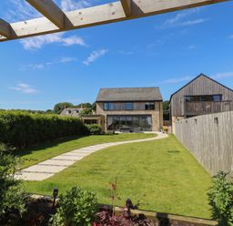 A garden with a lawn and pathway at The Joiners Cottage in Birling near Warkworth