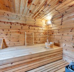 A sauna with wooden benches and a bucket at Oldfields