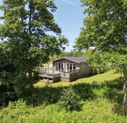 A cabin with a deck surrounded by trees at 20 Meadow Retreat in Dobwalls