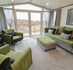 A living room with green furniture and a view at Willow's Way in Stranraer