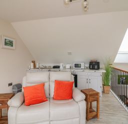 A living room with a sofa and kitchenette at Ard Uisce @ Estuary Bliss, Duncannon, County Wexford