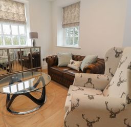 A living room with a sofa and a glass coffee table at The Lodge House in Dolphinholme near Galgate