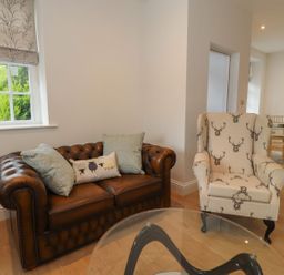 A living room with a sofa and an armchair at The Lodge House in Dolphinholme near Galgate
