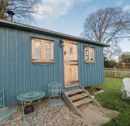 An outdoor area with a wooden shed and seating at Honeysuckle Hut, Potto Grange Farm Northallerton