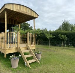 A wooden cabin with steps and planters at The Suffolk Hut in Lower Peover, Cheshire