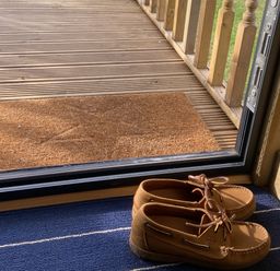 Shoes and a door mat by a sliding door at The Suffolk Hut, Lower Peover, Cheshire