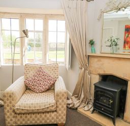 A living room with an armchair and fireplace at The Smithy Stow on the wold