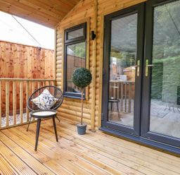 An outdoor deck with a chair and table at St. Chad's Lodge in Bodmin