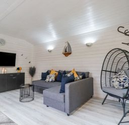 A living room with a television and sofa at St. Chad's Lodge in Bodmin