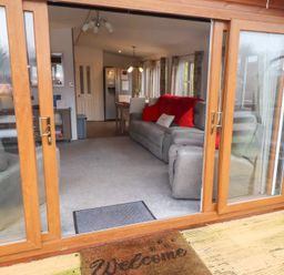 A living room with a sofa and dining area at Chloe's Cabin near Felmoor Holiday Park near Felton