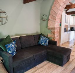 A living room with a sofa and kitchen area at Carwinley Mill House Cottage near Longtown