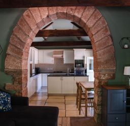 A kitchen with an archway and dining table at Carwinley Mill House Cottage Carwinley near Longtown